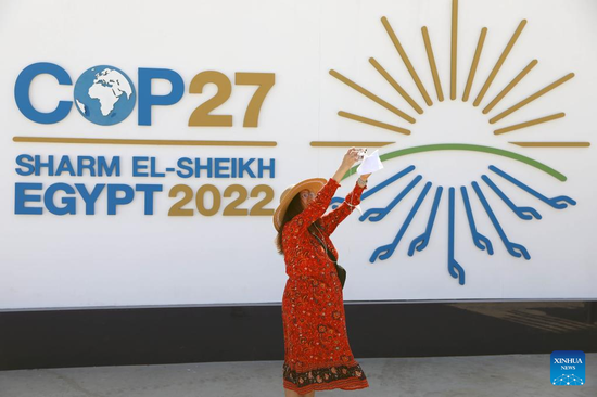 A woman takes pictures in front of a display board of the 27th Conference of the Parties of the United Nations Framework Convention on Climate Change (COP27) in Sharm El-Sheikh, Egypt, Nov. 6, 2022. The COP27 opened on Sunday in Egypt's coastal city of Sharm El-Sheikh in hopes to turn global climate finance pledges into action. (Xinhua/Sui Xiankai)