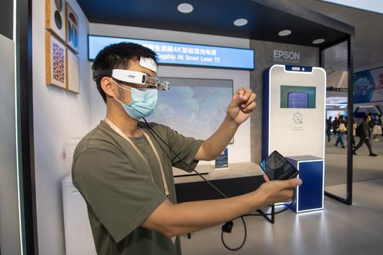 A visitor experiences a pair of AR glasses at the booth of Epson during the Light of Internet Expo in Wuzhen, east China's Zhejiang Province, Nov. 10, 2022. (Photo: Xinhua/Jiang Han)