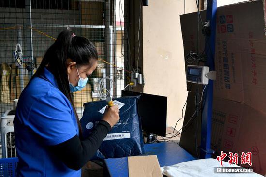 A worker weighs a parcel to be delivered to Myanmar, Ruili, Yunnan Province. (Photo/China News Service)