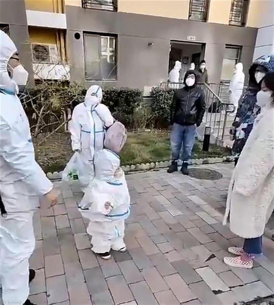 Video screenshot shows a kid is surrounded by warmhearted neighbors in Chaoyang District, Beijing, after his father decides to take him to a cabin hospital for quarantine.