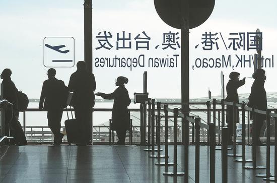Travelers enter a terminal at Beijing Capital International Airport to take flights on Thursday as some restrictions for travel were eased. (CUI JUN/FOR CHINA DAILY)