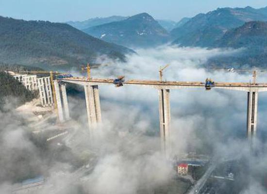 Cloud-shrouded Huangyujiang Bridge under construction in Guizhou