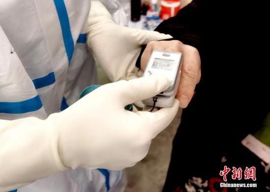 A doctor uses a fingertip pulse oximeter to test a patient's oxygen saturation of blood in a hospital in Wuhan. (Photo/China News Service)