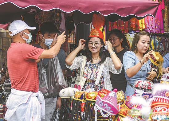 Tourists go shopping at the Xinjiang International Grand Bazaar in Urumqi, Xinjiang Uygur autonomous region, on July 7. (Photo/China News Service)