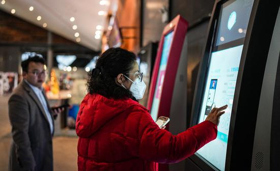 A woman touches the screen to get tickets on a self-service machine at a cinema in Guiyang, southwest China's Guizhou Province, Jan. 29, 2023. (Xinhua/Tao Liang)