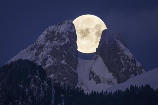 Spectacular scenery of full moon over mountain peaks