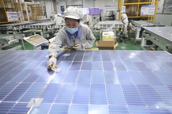 Workers produce solar batteries for export at a photovoltaic enterprise in Lianyungang, Jiangsu province, on Jan 3. (Photo/China Daily)
