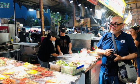 Mr Sonoyama, a member of the Japanese tour group, visits a night market in Aksu of Xinjiang region. (Photo/Courtesy of Guo Qiang)