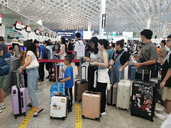 Passengers line up at check in gates at Shenzhen Baoan International Airport on Sunday. (WANG DONGYUAN/CHINA NEWS SERIVCE)