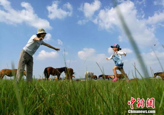 File photo of a girl and her grandparent playing in Saihanba, where barren land was turned into forest after six-decade-long efforts.(Photo:China News Service/ Yang Kejia）  