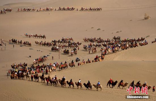 Tourists experience camel riding in Dunhuang, Gansu province. (Photo: China News Service/ Zhang Xiaoliang)