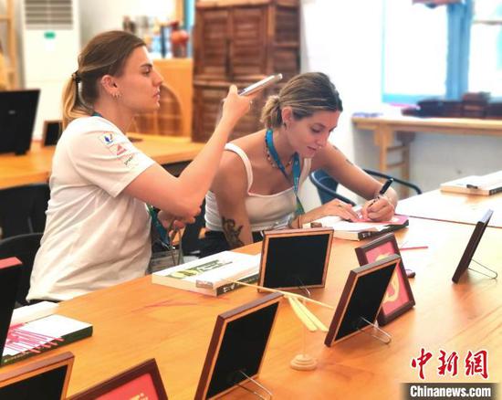 Foreign athletes make the intangible cultural heritage of bamboo weaving in Chengdu Universiade Athletes' Village on July 30. (Photo: China News Service/ Shan Peng)