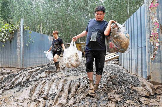 Villagers return to Linzitou village in Zhuozhou, Hebei province, on Monday. They will soon begin dredging and cleaning up their mud-filled home. (WU XIAOHUI/CHINA DAILY)