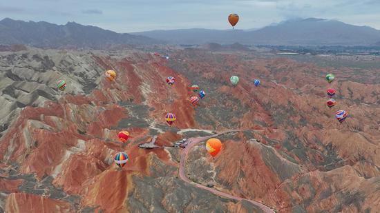 Colorful hot air balloons paint sky over Danxia landform in Guansu