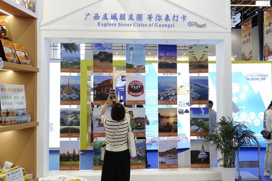 A visitor takes photos at Guangxi International Sister Cities at CAEXPO held in . (Photo by Liao Zhang Li)