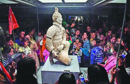 Visitors admire a terracotta warrior on display at Emperor Qinshihuang's Mausoleum Site Museum in Xi'an, Shaanxi province, on Wednesday. On average, 60,000 tourists visit the museum daily during the holidays. (YUAN JINGZHI/FOR CHINA DAILY)
