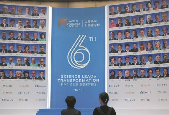 Visitors view a poster outside the venue of the sixth World Laureates Forum, which opened on Monday in the Lingang Special Area of Shanghai. (GAO EROIANG/CHINA DAILY)
