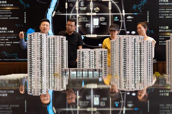 A salesman (left) introduces a residential project to potential homebuyers in Taiyuan, Shanxi province, on July 14. (Photo: Wei Liang/China News Service)