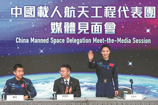 Shenzhou XIII astronaut Wang Yaping waves during a media briefing to introduce the latest developments of China's manned space program at the Hong Kong Convention and Exhibition Centre in Wan Chai on Tuesday. The media briefing was also attended by Lin Xiqiang (center), deputy director of the China Manned Space Agency, and Shenzhou XIV astronaut Chen Dong. (ANDY CHONG/CHINA DAILY)