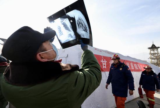 A doctor checks X-ray films on Thursday at a resettlement site in Jishishan county, Gansu province. A medical aid team from the Gansu Provincial Hospital are treating the quake-affected people at a mobile field hospital which is capable of carrying out CT scans, laboratory tests and surgeries. WEI XIAOHAO / CHINA DAILY