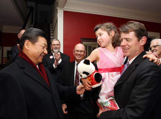 Xi Jinping (L) presents the granddaughter of his old friend Sarah Lande with a panda doll in Muscatine, a small city in Iowa, the United States, Feb. 15, 2012. (Photo/Xinhua)