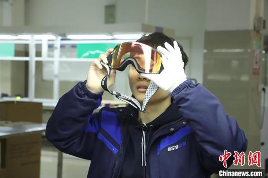 An inspector at a sports factory checks the quality of ski goggles. (Photo/China News Service)