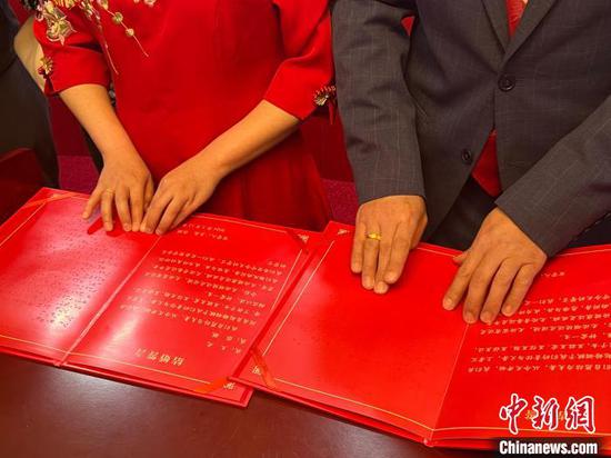 Wang Guang and Zhang Yu read the Braille version of marriage vows through touch. (Photo/China News Service)