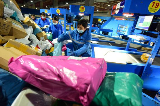 Workers sort packages at a logistics park in Lianyungang, Jiangsu province, on March 7. （ZHANG ZHENGYOU/FOR CHINA DAILY）