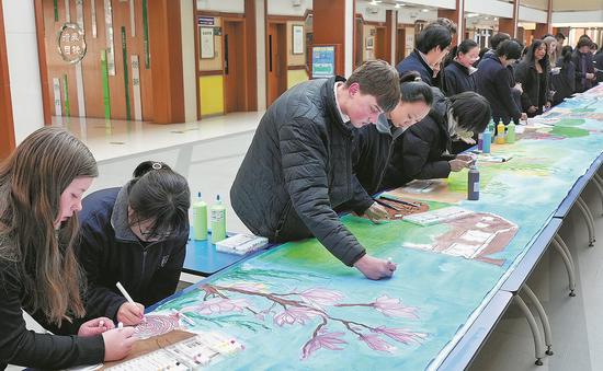 U.S. students from Muscatine High School paint with Chinese students during a visit to Shijiazhuang Foreign Language School in Hebei province in January. (CHINA DAILY)
