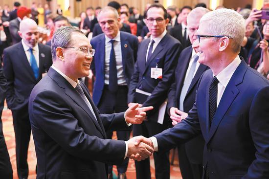 Premier Li Qiang shakes hands on Sunday with Apple CEO Tim Cook after the opening ceremony of the China Development Forum 2024 in Beijing. (FENG YONGBIN/CHINA DAILY)