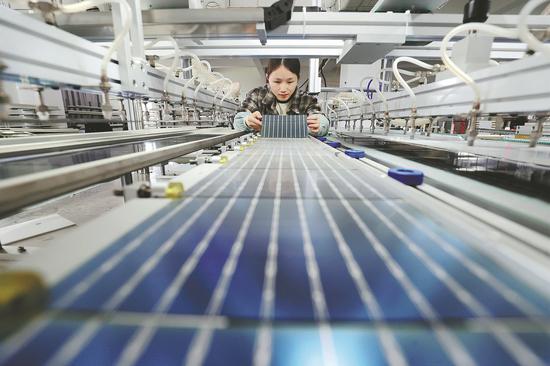 An employee works on a photovoltaic production line at a tech company in Huzhou, Zhejiang province. (Photo: For China Daily/ by Xie Shangguo)