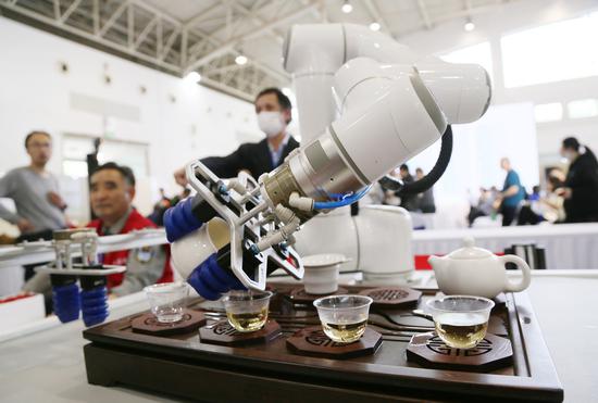 A robot serves tea to visitors during a tea expo in Beijing in April. (WU CHANGQING/FOR CHINA DAILY)