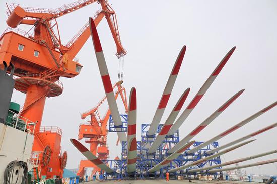 Wind turbine blades are loaded onto a freighter at Yantai Port in Shandong province in April. (TANG KE/FOR CHINA DAILY)