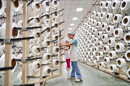Employees work on the production line of a textile company in Ganzhou, Jiangxi province. (ZHU HAIPENG/FOR CHINA DAILY)