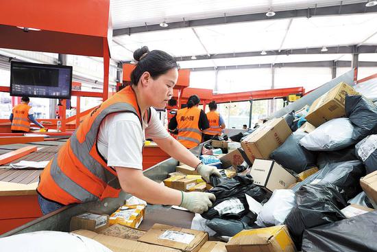 Staff members at the joint distribution center in Yucheng handle parcels with the help of a sorting machine. (Photo by ZHANG YU/CHINA NEWS SERVICE)