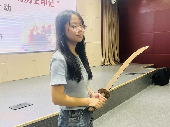 Hu Yuehong, student representative of Nankai University’s social practice team, shows the participants a machete collected during a field investigation in North China’s Hebei province on Aug. 21 in Beijing. It was used by a former Chinese worker in WWI. (Photo: China News Network/Lin Zhuowei)