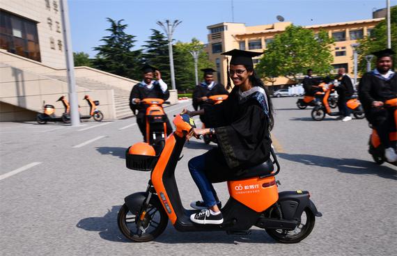 Students ride e-bikes to get their graduation photographs clicked on the campus of a university in Qingdao on June 17, 2024.