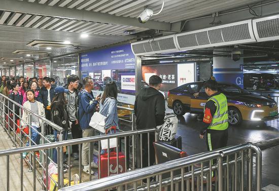 Passengers wait in a queue for taxis at Beijing South Railway Station on Monday as the National Day holiday comes to an end. (DENG WEI/FOR CHINA DAILY)