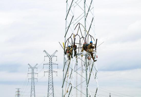 State Grid employees inspect a transmission tower in Taizhou, Jiangsu province, in September. (TANG DEHONG/FOR CHINA DAILY)