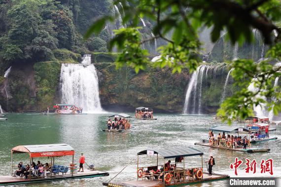 Tourists took sightseesing boats to visit the Detian Waterall in Guangxi. (File photo/China News Service)