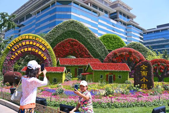 Tourists take photos in front of a flowerbed in Beijing, June 27, 2021. (Photo: China News Service/Hu Qingming)