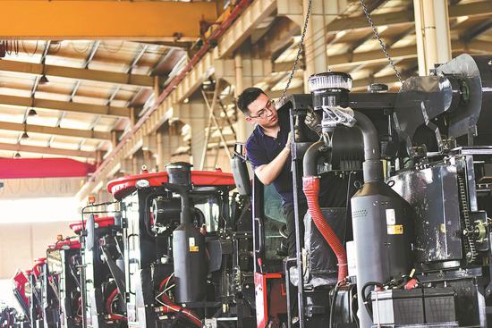 An employee works on the production line of a combine harvester manufacturer in Qingzhou, Shandong province. (WANG JILIN/FOR CHINA DAILY)