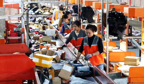 Workers sort express delivery packages at a courier logistics company in Lianyungang, Jiangsu province, on Monday. (GENG YUHE/FOR CHINA DAILY)