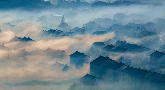 Morning mist transforms village into ink painting