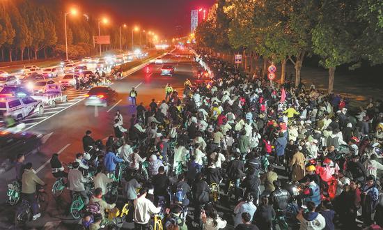 Zhengkai Avenue is thronged with cyclists in Zhengzhou, Henan province, on Friday. Extra police officers were deployed and guardrails installed to separate motor vehicle lanes from cycle lanes to ensure safety. (Photo/For China Daily)