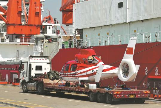 A vehicle transfers a helicopter from the icebreaker Xuelong, or Snow Dragon, at a dock in Shanghai on Tuesday. The polar research icebreaker Xuelong'sreturn on that day marked the near completion of China's 41st Antarctic expedition. (Photo by Gao Erqiang/China Daily)