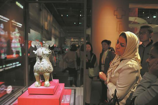 Visitors admire a bronze zun ritual vessel that dates back to the Shang Dynasty (c.16th century — 11th century BC) while perusing the This is the Shang exhibition at the Grand Canal Museum of Beijing on Sunday. (JIANG DONG/CHINA DAILY)