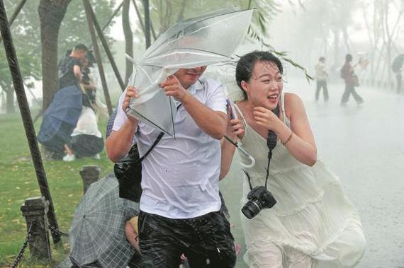 Tourists at the West Lake's Bai Causeway in Hangzhou, Zhejiang province, are caught off guard by strong winds and brief heavy rainfall on Tuesday due to Danas, the fourth typhoon of the year. (LI ZHONG/FOR CHINA DAILY) Tourists at the West Lake's Bai Causeway in Hangzhou, Zhejiang province, are caught off guard by strong winds and brief heavy rainfall on Tuesday due to Danas, the fourth typhoon of the year. (LI ZHONG/FOR CHINA DAILY)