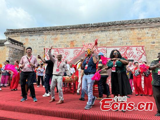 International journalists interact with the performers on the stage, in Guanxi Xinwei, a Hakka walled complex in Longnan, east China's Jiangxi Province, July 16, 2025. (Photo: China News Network/ Huang Fang)