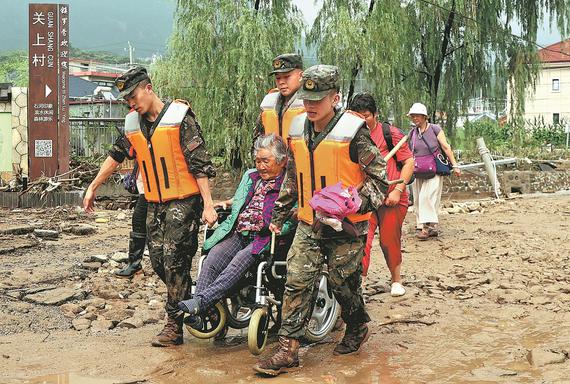 Members of the People's Armed Police Force help evacuate an elderly woman on Monday in Beijing's Pinggu district, which has also been affected by the flooding. (BAI JIKAI/FOR CHINA DAILY)